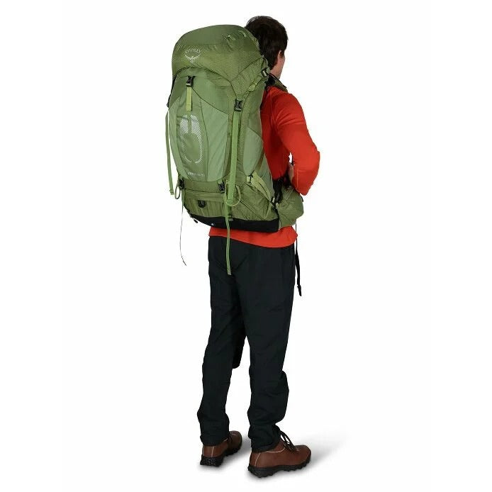 Person wearing a large green backpack on a white background