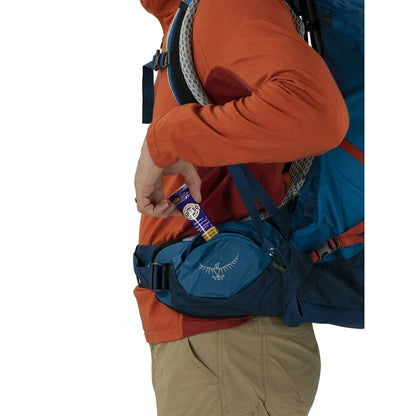Person wearing a blue Osprey backpack with a product in hand on a white background