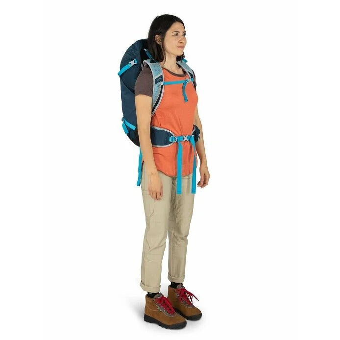 Woman wearing a large blue and gray backpack on a white background