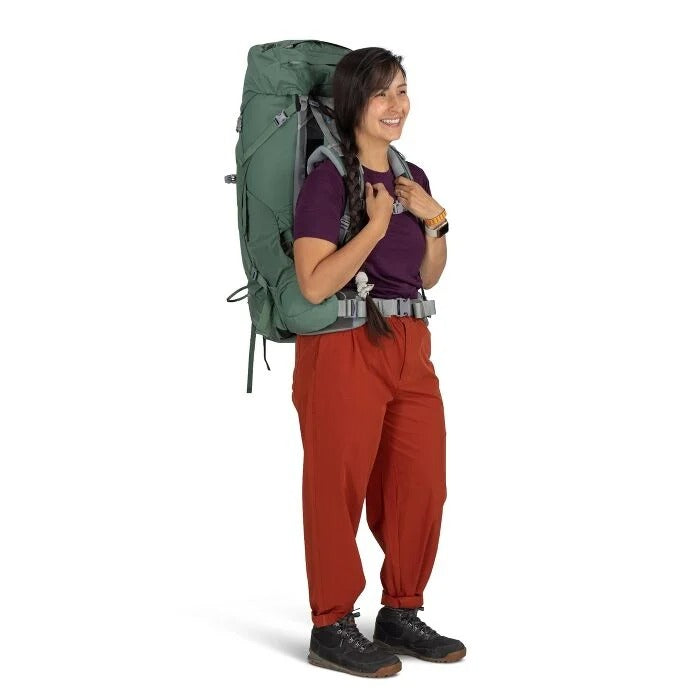 Person wearing a large green backpack on a white background