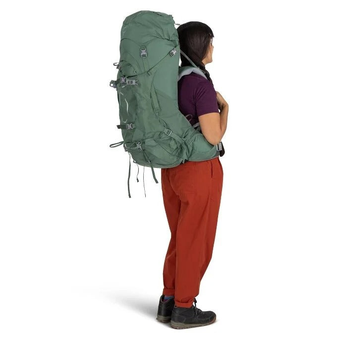 Person wearing a large green backpack on a white background
