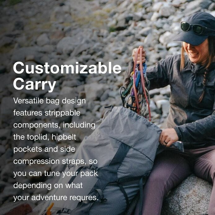 Person sitting on rocks with a customizable bag, surrounded by nature.