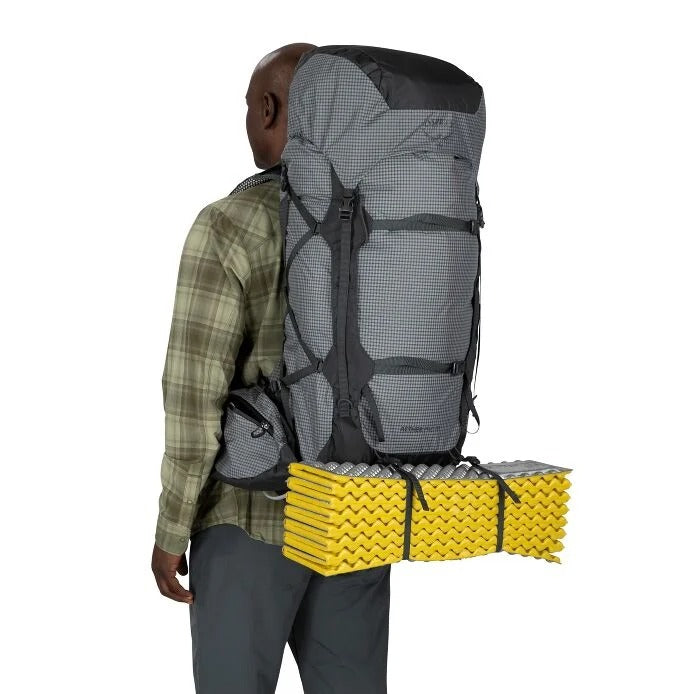 Person wearing a large gray backpack with yellow sleeping pad on a white background