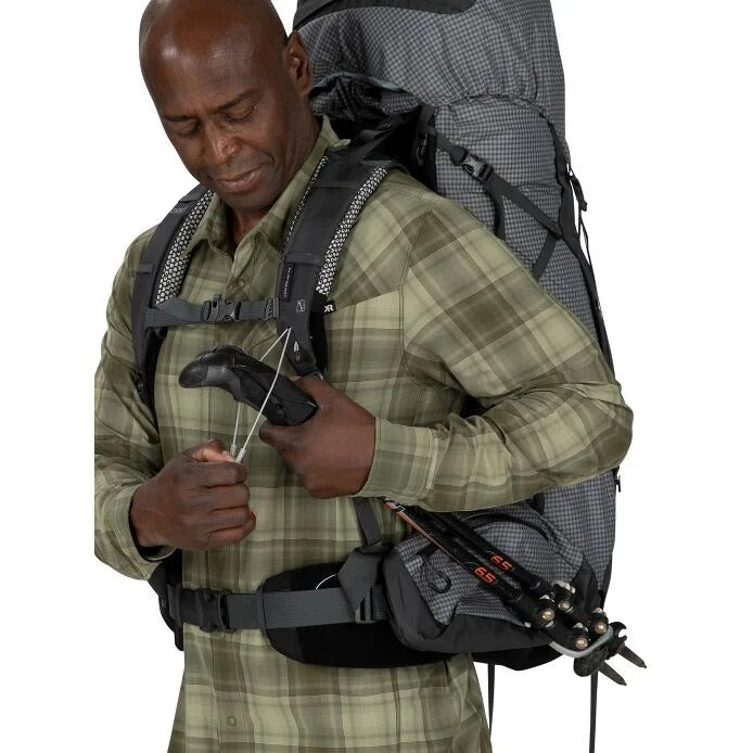 Man adjusting climbing gear with a backpack on a white background
