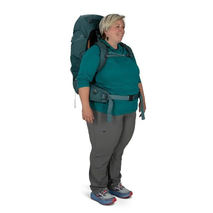 Person wearing a large green backpack on a white background