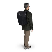 Man wearing a black Osprey backpack on a white background