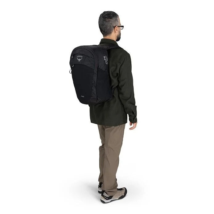 Man wearing a black Osprey backpack on a white background