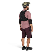 Person wearing a pink shirt, maroon shorts, black backpack, and helmet on a white background