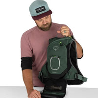 Man holding a green Osprey backpack on a white background