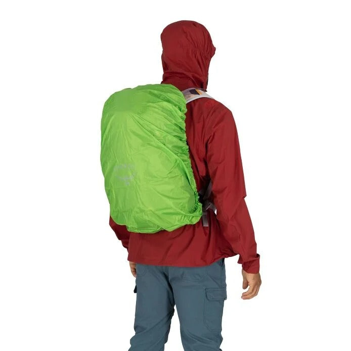 Person wearing a red jacket with a green backpack cover on a white background