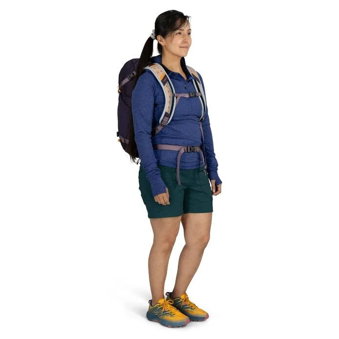 Person wearing a blue shirt, green shorts, and a backpack on a white background