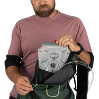 Man holding an Osprey hydration pack with a white background