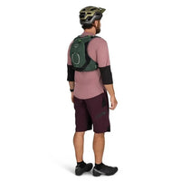 Person wearing a pink shirt, maroon shorts, black shoes, and a green backpack on a white background