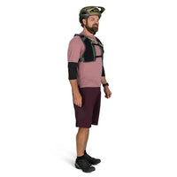 Man wearing a pink shirt, maroon shorts, and black helmet on a white background
