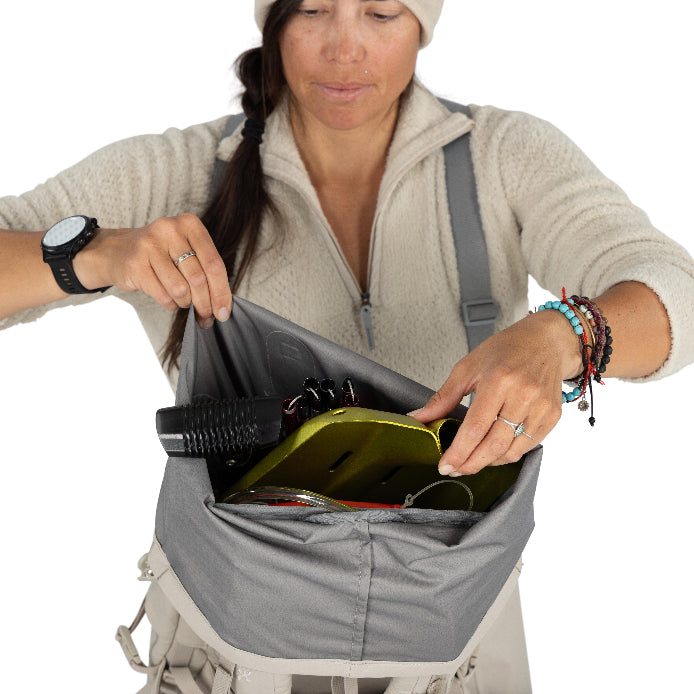 Person organizing items in a backpack with a white background
