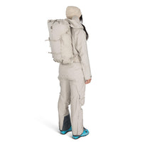 Person wearing a beige backpack and snow pants on a white background