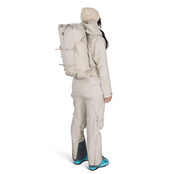 Person wearing a beige backpack and snow pants on a white background