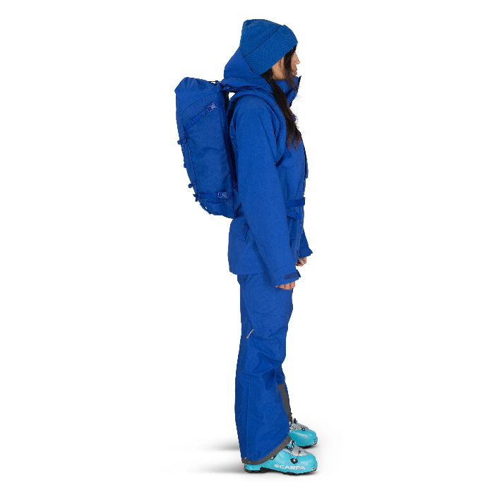 Person wearing a blue snowsuit with a backpack on a white background