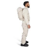 Man wearing a beige winter outfit with a backpack on a white background