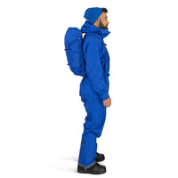 Person wearing a blue snowsuit with a backpack on a white background