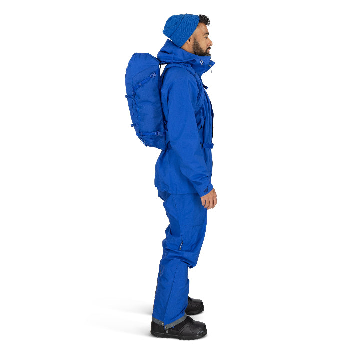 Person wearing a blue snowsuit with a backpack on a white background