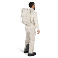 Man wearing a beige backpack and hiking pants on a white background