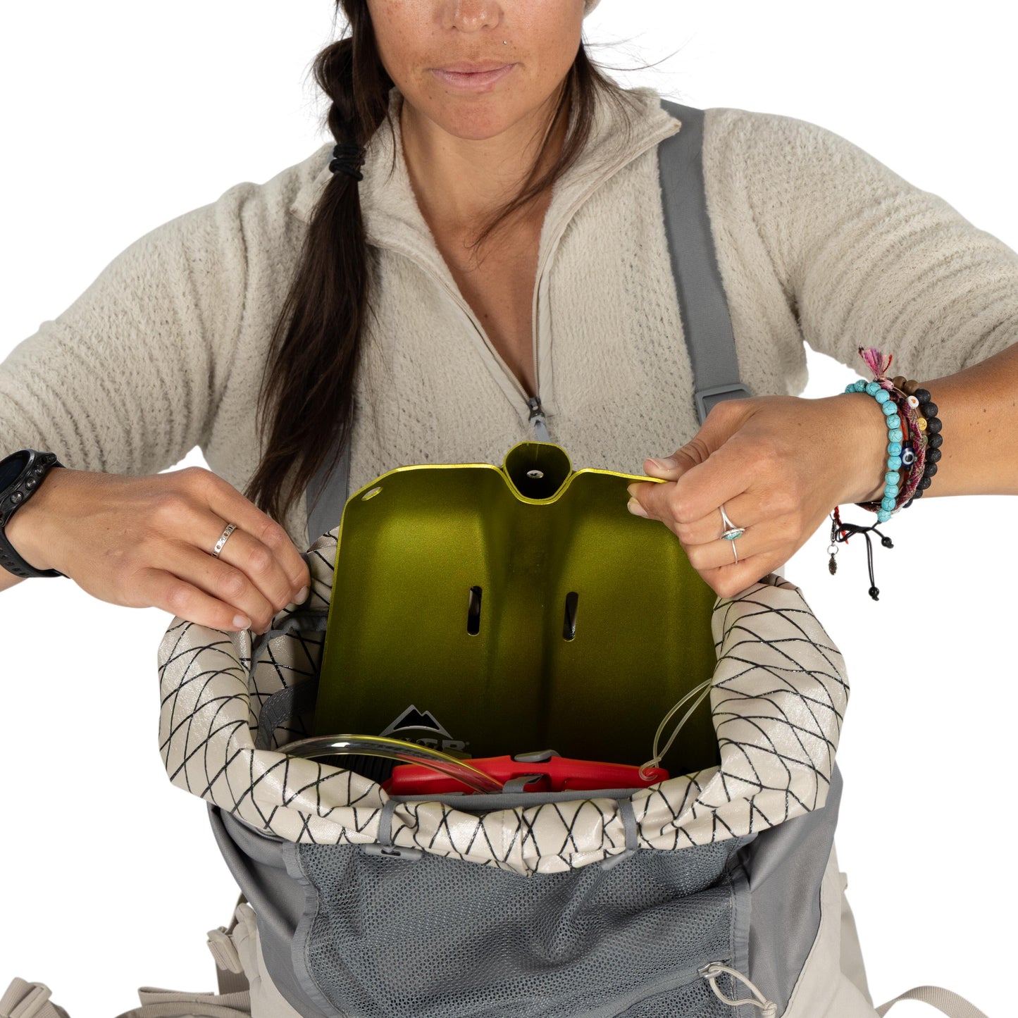 Person opening a backpack with a green helmet inside, on a white background