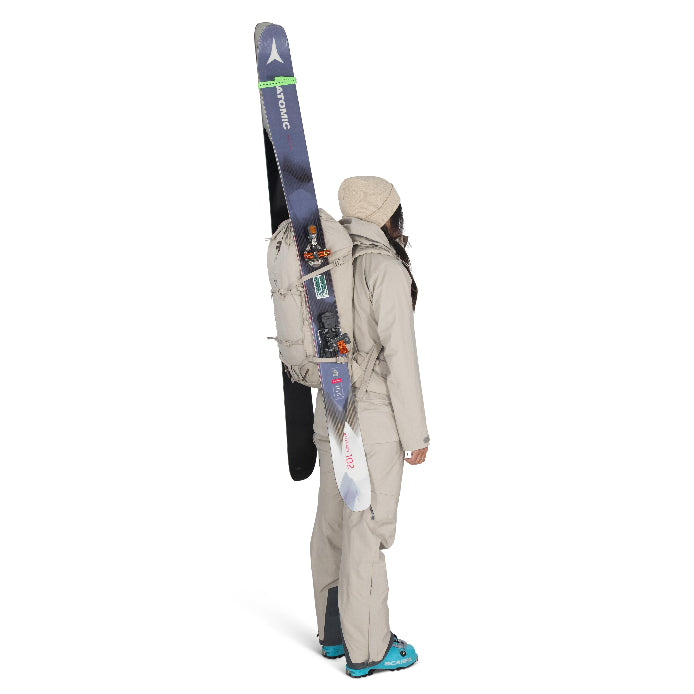 Person wearing a backpack with skis on a white background
