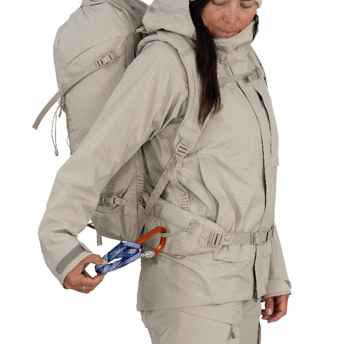 Person wearing a beige hiking outfit with a backpack on a white background