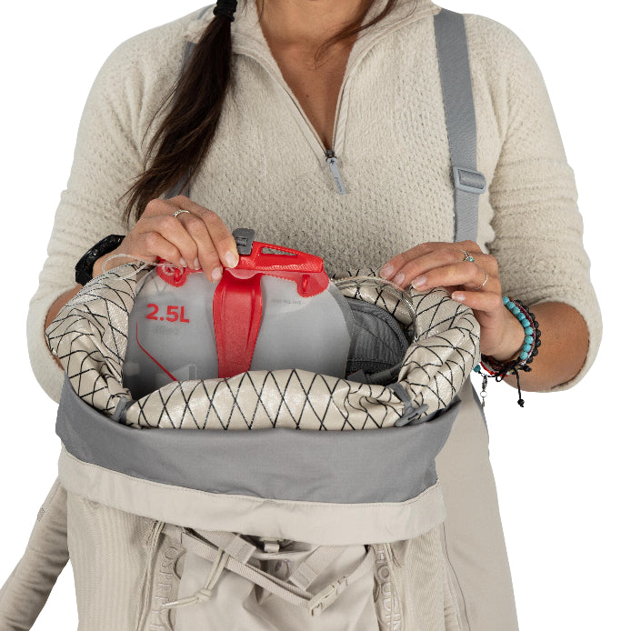 Person holding a 2.5L water bottle in a hydration pack against a white background