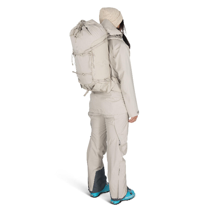 Person wearing a beige backpack and snow pants on a white background