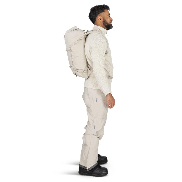 Man wearing a beige winter jacket and pants with a large backpack on a white background