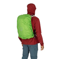 Person wearing a red jacket with a green backpack cover on a white background