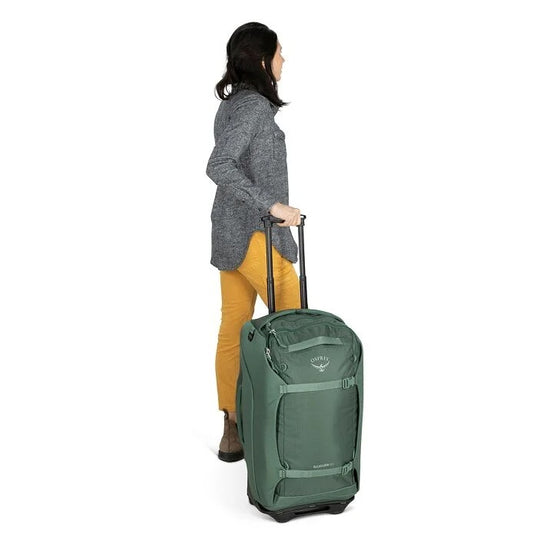 Person pulling a green suitcase on a white background