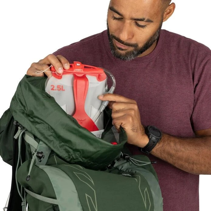 Man holding a green backpack with a water bottle inside, on a white background