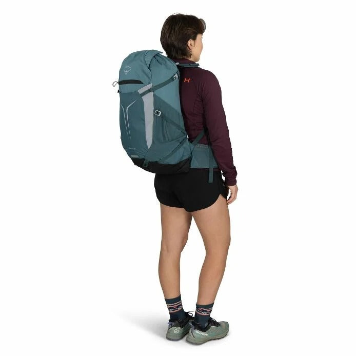 Teal hiking backpack worn on back with adjustable straps and side access pocket
