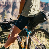 Person wearing Rapha cycling shorts on a mountain bike with a scenic background