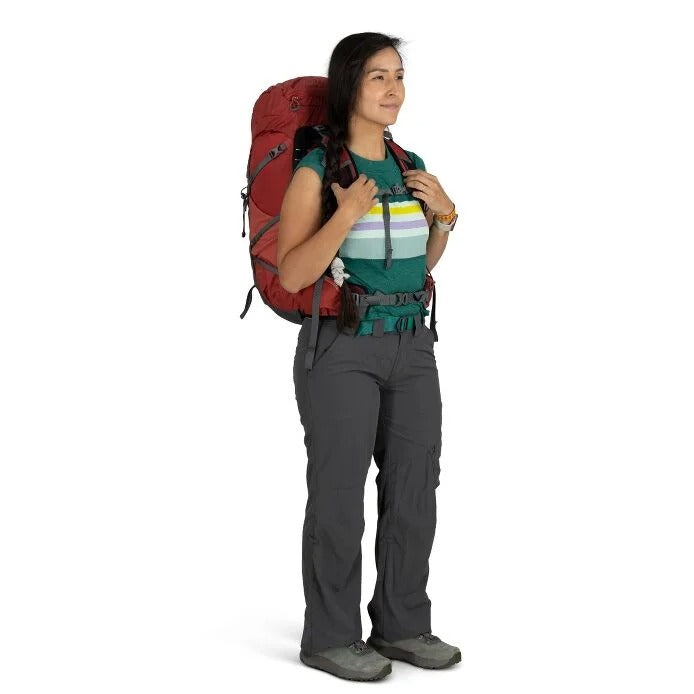 Person wearing a red backpack and hiking gear on a white background