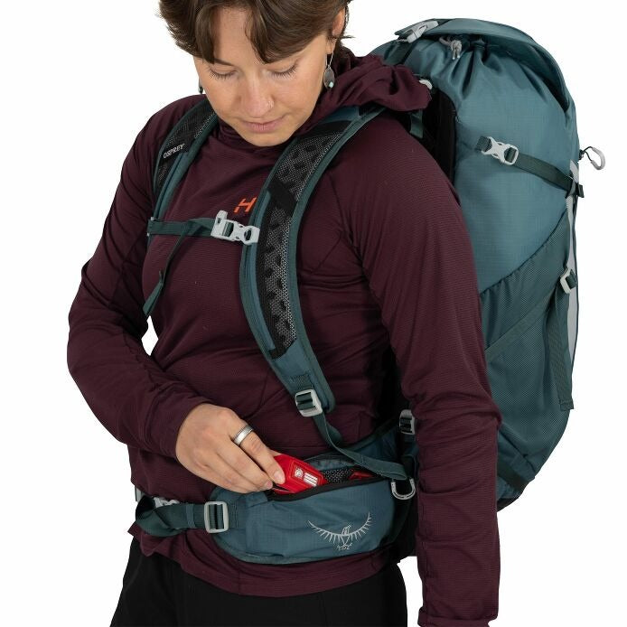 Teal hiking backpack close-up showing front harness straps and opened waist pocket