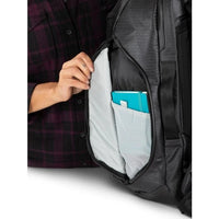 Person opening a black backpack with a blue item inside, wearing a plaid shirt.