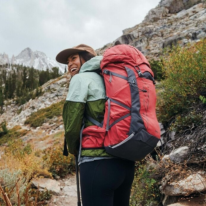 Person hiking in a mountainous area with a red backpack