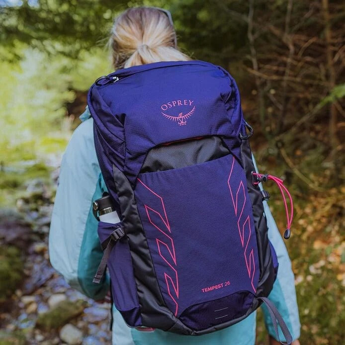 Person wearing a purple Osprey backpack in a natural setting