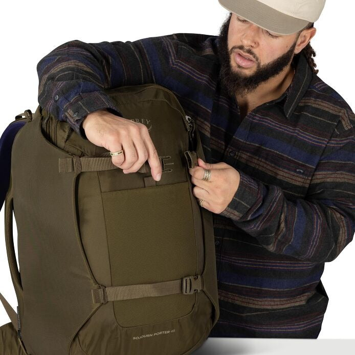 Olive green travel pack with front pocket and adjustable straps, open for access