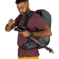 Man preparing for outdoor activity with a backpack and climbing gear on a white background