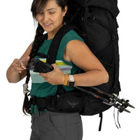 Woman with a large black backpack holding sunglasses, on a white background