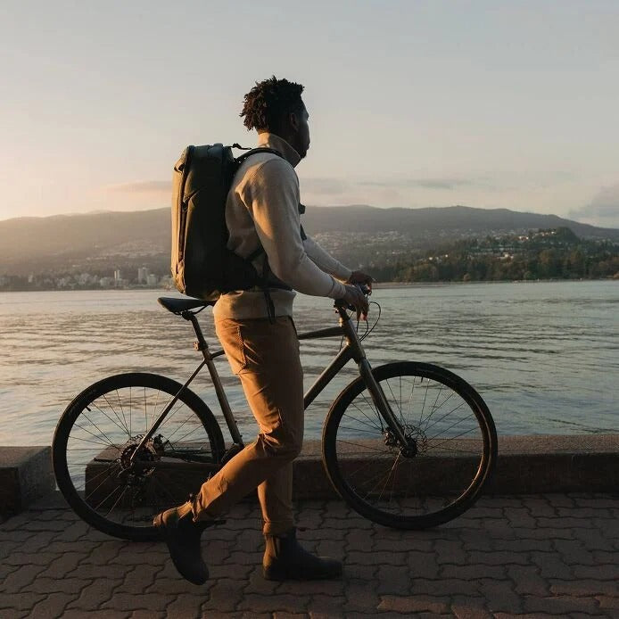 Person with a bicycle by a waterfront at sunset