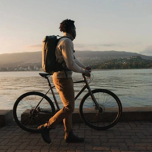 Person with a bicycle by a waterfront at sunset