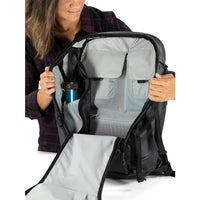 Person holding a black backpack with a blue water bottle inside, on a white background