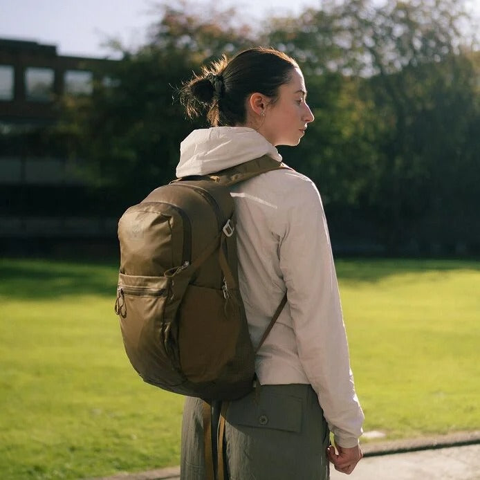 Woman with a brown backpack walking outdoors on a sunny day