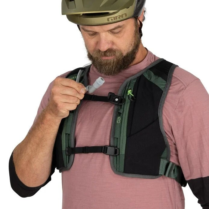 Man adjusting a green and black backpack on a white background